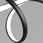Macro of the Clérachic pendant's textured matt black ribbon curling in a loop, with the white LED diffuser glowing along its inner edge.
