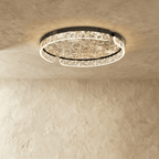 Clérachic round ceiling light with a black metal frame and a lit marbled glass ring, seen against a textured plaster ceiling.
