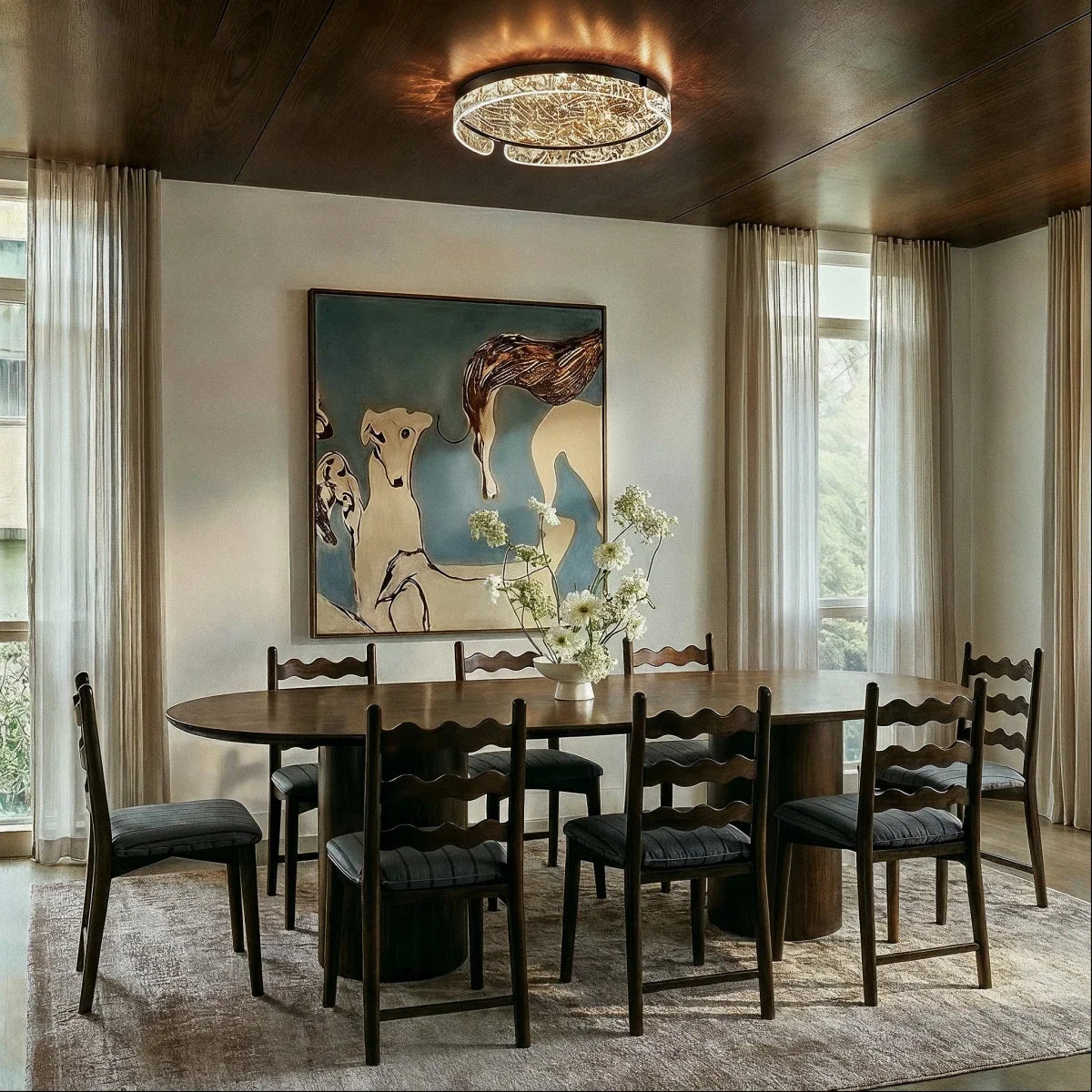 Clérachic round ceiling light glowing above an oval walnut dining table, chairs and a large painting in a calm dining room.