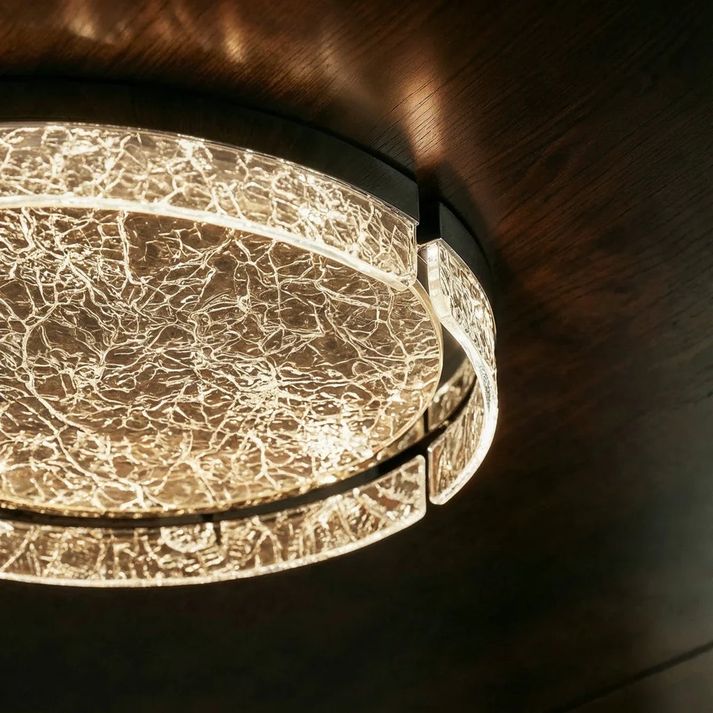Close-up of the Clérachic ceiling light, its cracked-ice marbled glass ring and centre glowing warmly against a dark wood ceiling.