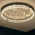 Clérachic round ceiling light viewed from below, lit, with a black metal rim and bright marbled glass ring and centre.
