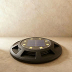 Seen from above and unlit, the black solar disc light shows its circular solar panel and eight LED points in this Clérachic hero shot.