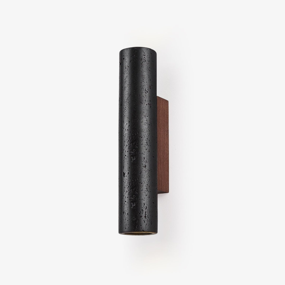 A black travertine cylinder wall light on a walnut backplate, switched off against a plain white backdrop, from Clérachic.
