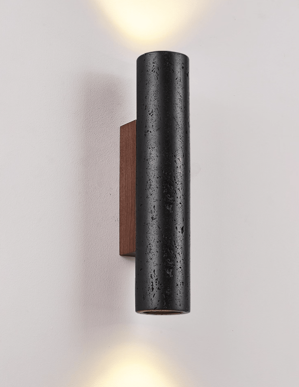 A Clérachic cylinder wall light sends light both up and down a pale wall, its walnut backplate visible at the side.