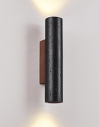 A Clérachic cylinder wall light sends light both up and down a pale wall, its walnut backplate visible at the side.