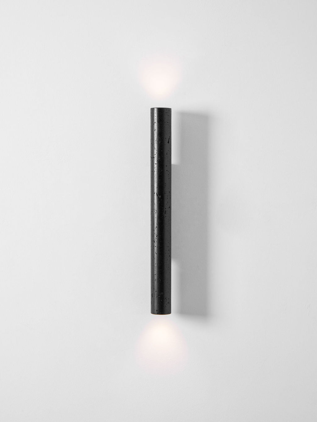 A tall Clérachic wall light throws a faint glow above and below it on a pale, clean wall.