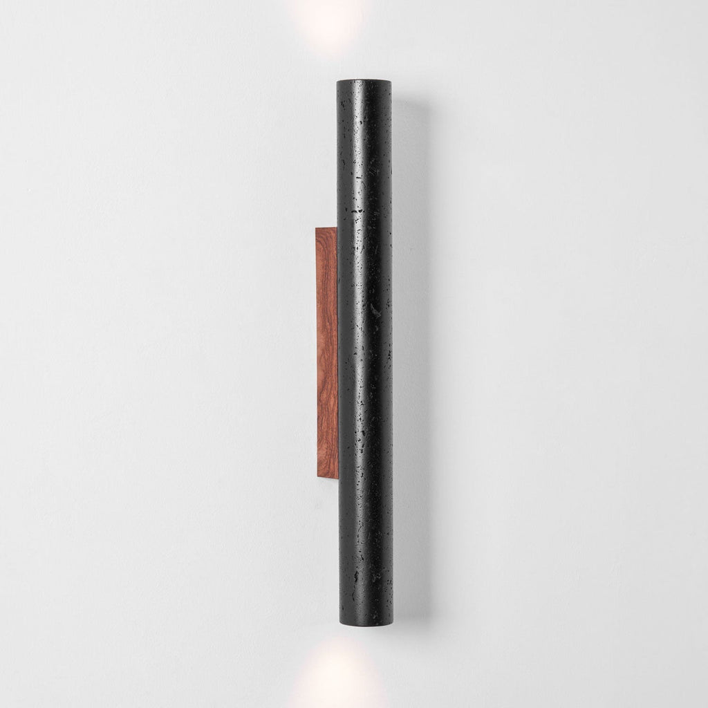 A tall Clérachic black stone cylinder with a walnut backplate, with light just visible at the top and bottom edges.