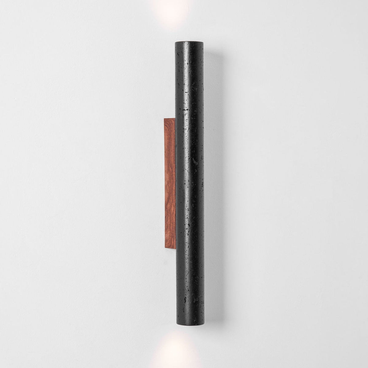 A tall Clérachic black stone cylinder with a walnut backplate, with light just visible at the top and bottom edges.