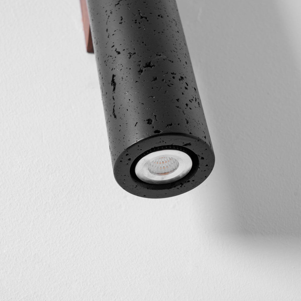 Close view of the lower end of this Clérachic black travertine cylinder, showing the white light source set in the opening.