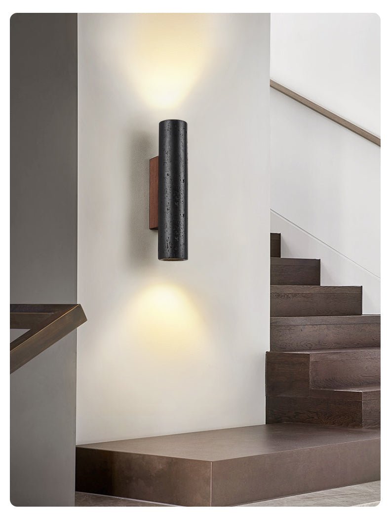 A Clérachic wall light lights a pale stairwell wall, with dark timber steps and a landing below.