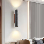 A Clérachic cylinder wall light glows above a living space with a ribbed wall panel and soft furnishings.