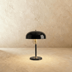Clérachic dome table lamp in glossy black enamel with a brass neck and base ring, photographed against a plain backdrop.