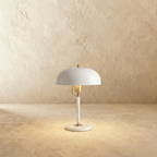 Clérachic dome table lamp in white enamel with a brass neck and base ring, photographed against a plain studio backdrop.