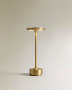 Clérachic's gold cordless table lamp stands tall with a slim aluminium stem and round tray-like shade.