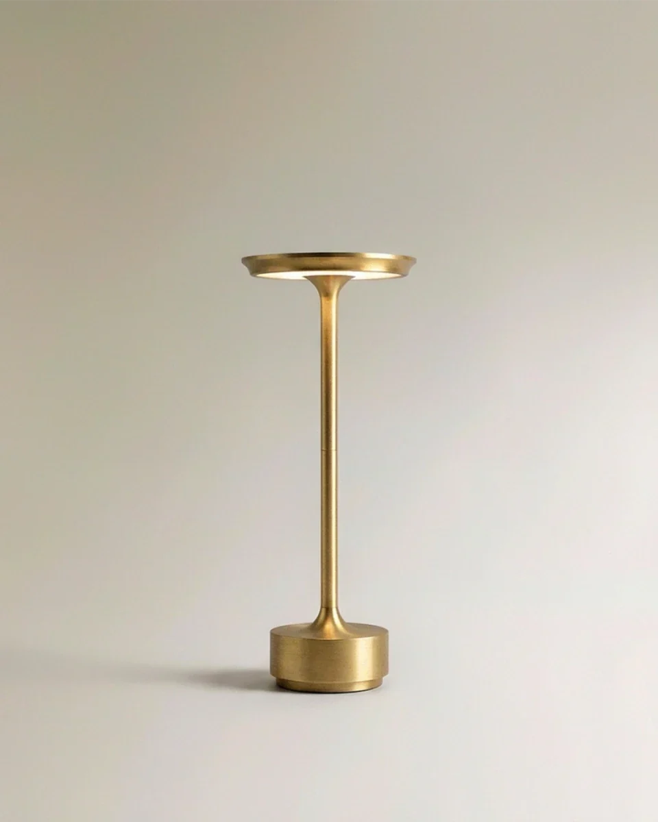 Clérachic's gold cordless table lamp stands tall with a slim aluminium stem and round tray-like shade.