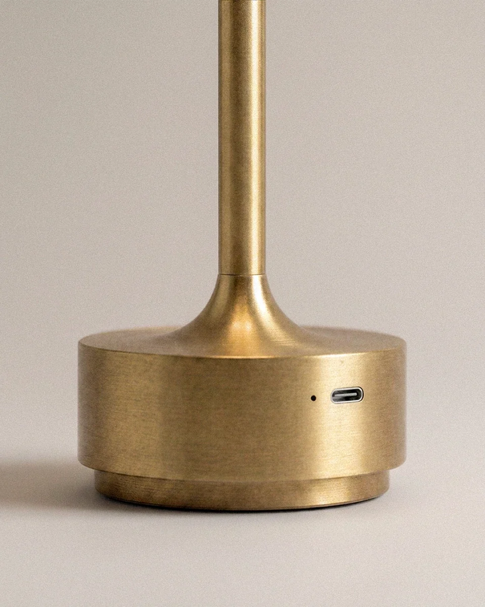 Close-up of the Clérachic gold lamp's base shows its USB-C charging port and brushed metal finish.