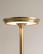A close view of the Clérachic gold lamp's saucer-shaped top reveals its warm glowing LED disc.