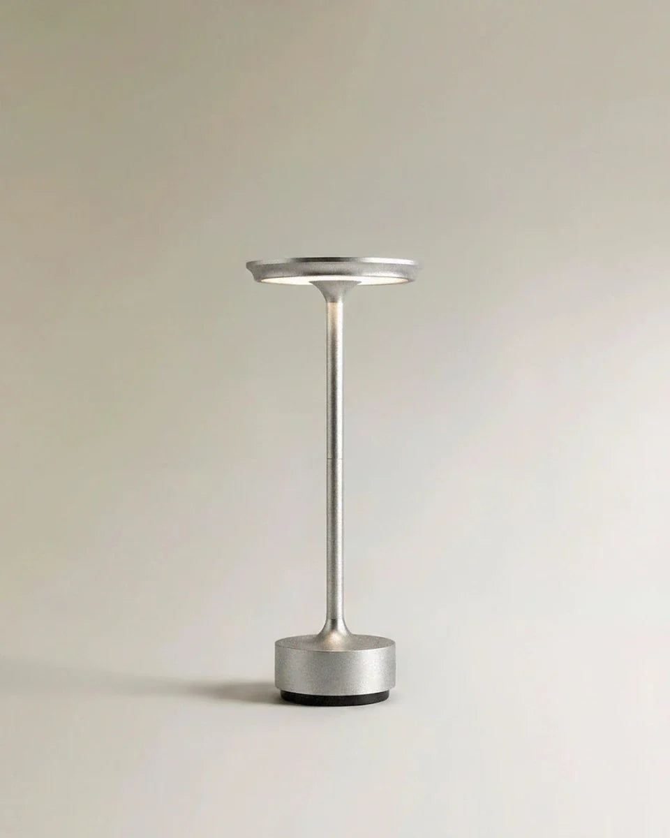 Clérachic's silver cordless table lamp stands upright, its slim aluminium column catching soft studio light.
