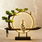 Clérachic incense-burner lamp lit bright gold, a seated white Guanyin figure glowing against a plain backdrop.
