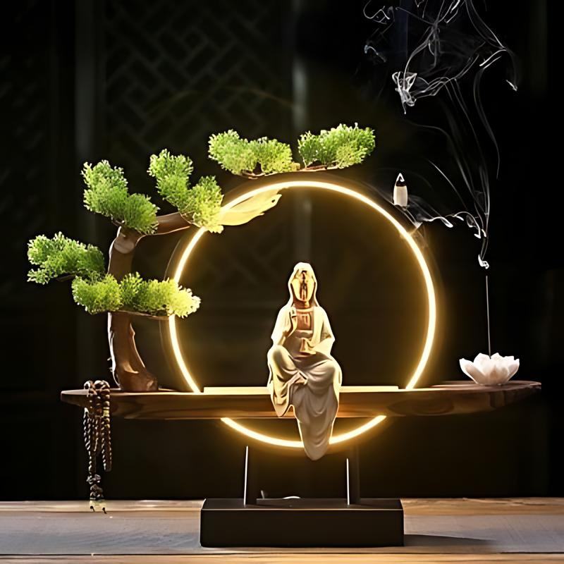 Clérachic incense-burner lamp lit bright gold on a dark wood floor, a seated white Guanyin figure glowing.