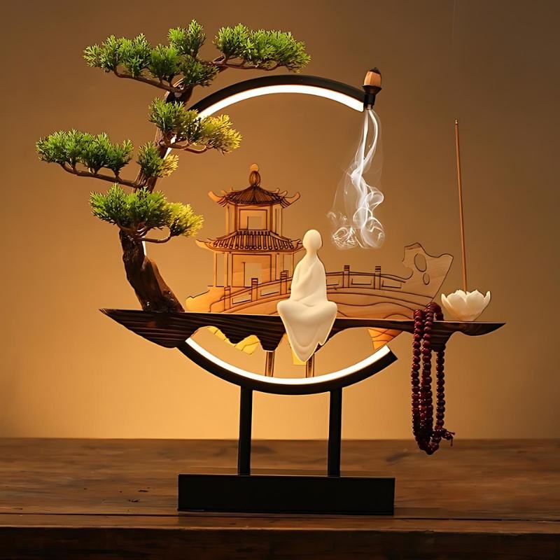 Clérachic incense-burner lamp lit warm on a wood table, a standing white figure beside a glowing pagoda.