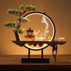 Clérachic incense-burner lamp lit warm on a wood table, a white deer figure beside a glowing pagoda scene.