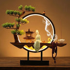 Clérachic incense-burner lamp lit warm on a wood table, a seated jade-green Guanyin figure and pagoda.