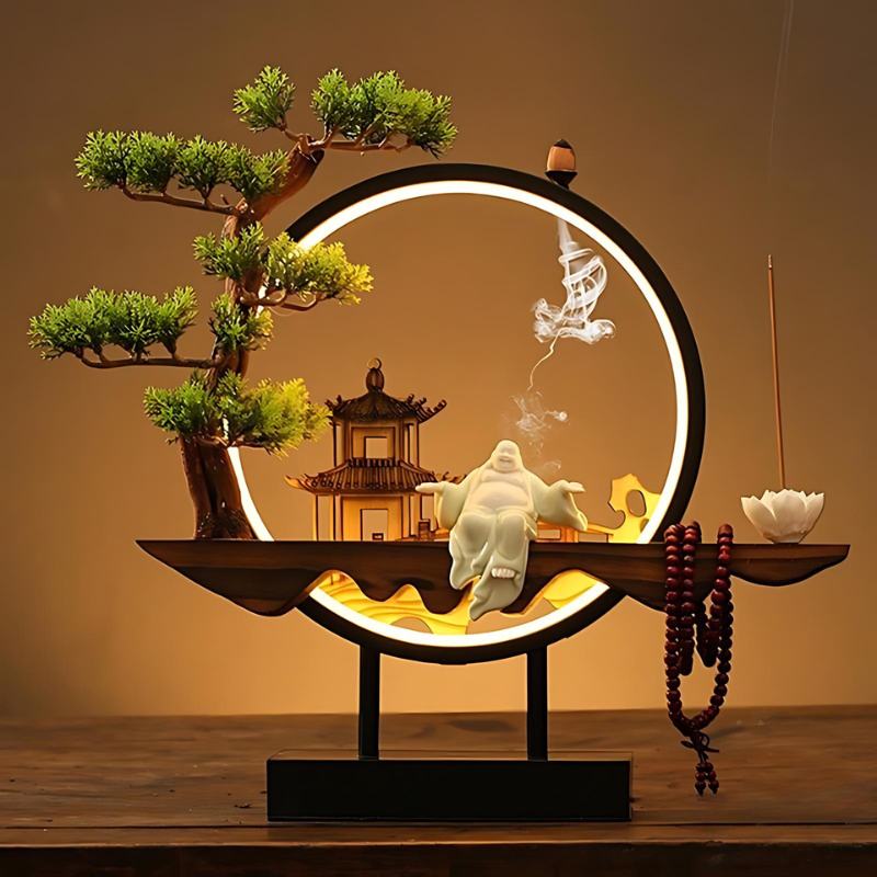 Clérachic incense-burner lamp lit warm on a wood table, a laughing Buddha figure beside a glowing pagoda.