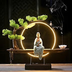 Clérachic incense-burner lamp lit bright gold against a dark backdrop, a seated white Guanyin figure glowing.
