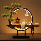 Clérachic incense-burner lamp lit warm on a wood table, a laughing Buddha figure glowing beside a pagoda.