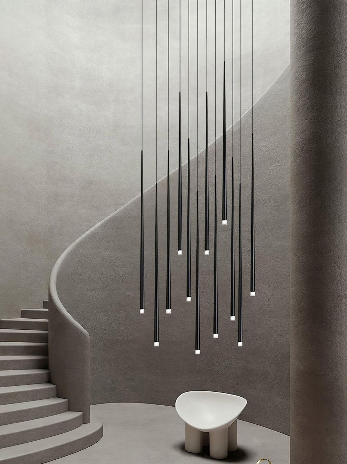 Tall group of black tapered pendants dropping beside a curving plaster staircase, with a pale sculptural stool below, this Clérachic pendant.