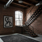 Beside a brick wall and open black steel stairs, a Clérachic pendant cluster hangs from a round canopy above a dark shaggy rug.