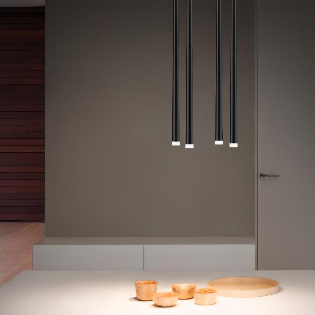 Four black tubes in two pairs hang against a taupe wall above a pale counter with small wooden bowls, a Clérachic pendant.
