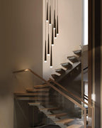 Cone-shaped black pendants cascade beside open timber stairs with a glass balustrade, tips glowing warm, from Clérachic.