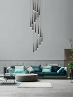 Spiralling cluster of black tapered pendants hangs in a double-height room above a teal sofa and round pouffe, a Clérachic pendant.