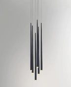 Close grouping of black tapered pendants at staggered lengths against a pale grey wall, tips lit, a Clérachic pendant.