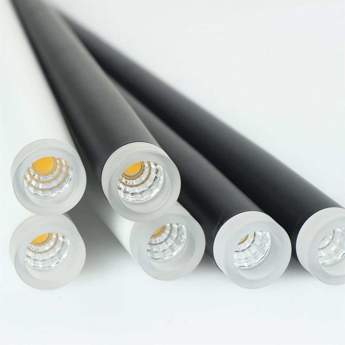 Close view of the frosted diffuser and LED at the tip of these Clérachic pendant tubes, one tube shown in white beside the black.