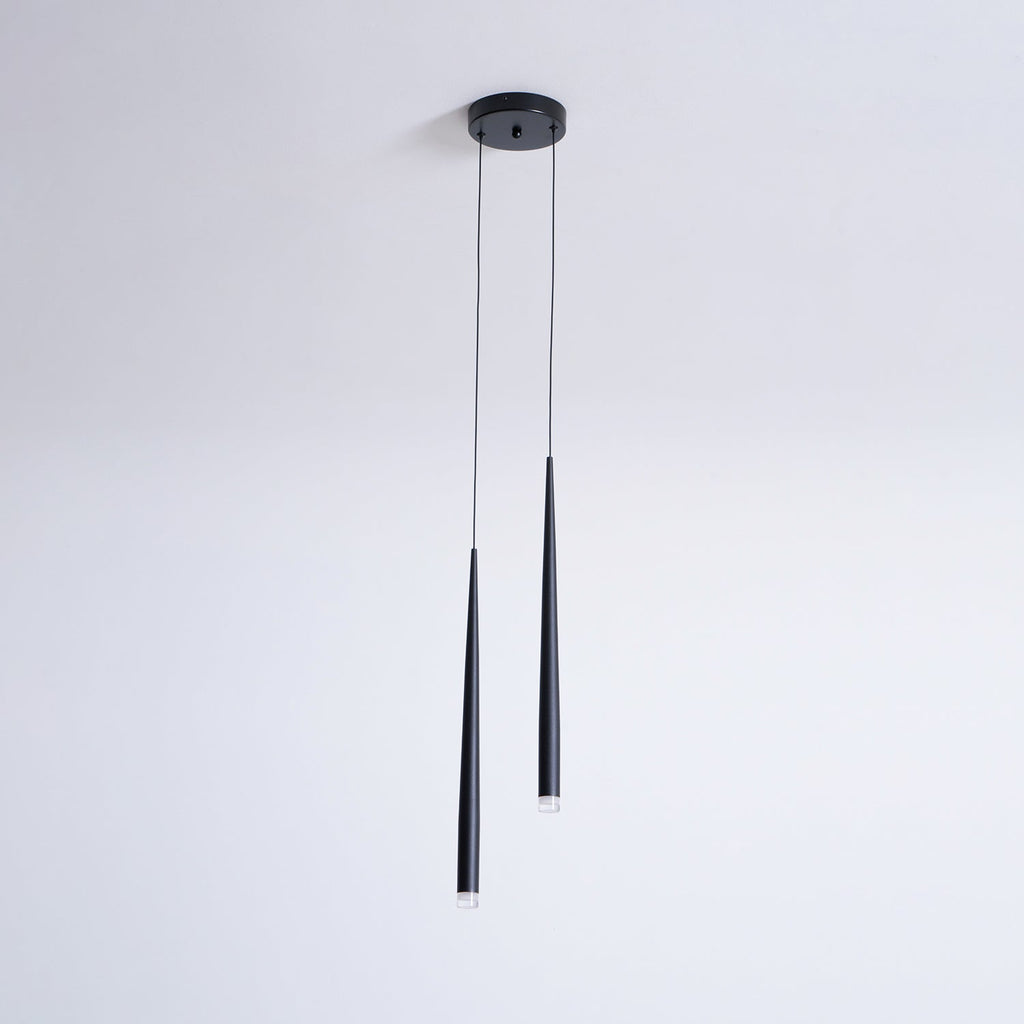 Two black tapered pendants of unequal length hang from a round canopy on a plain pale wall, from Clérachic.