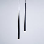 Two black tapered pendants seen close up against a soft grey wall, with the lit tips just visible, from Clérachic.