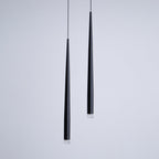 Close view of two black cone pendants at different lengths, matte finish and clear lens at the tips, from Clérachic.