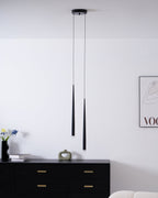 Wider room view of two black pendants above a black chest, with flowers, a vase and a cream sofa edge, a Clérachic pendant.