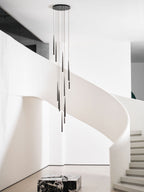 Tall view of this Clérachic pendant cluster in a white stair hall, with steps and a marble block at the base.