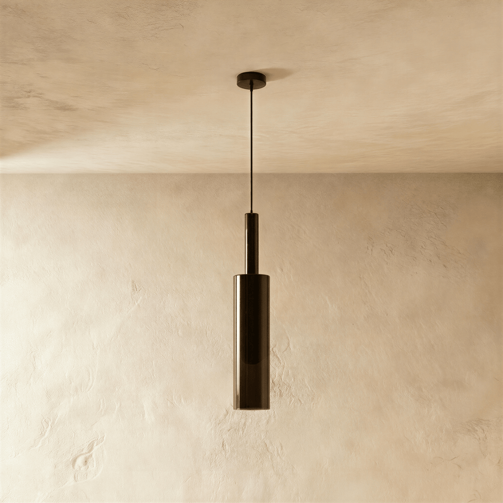 Unlit and straight-on, the black-tinted glass pendant's cylindrical shade hangs against a bare plaster wall, Clérachic hero shot.