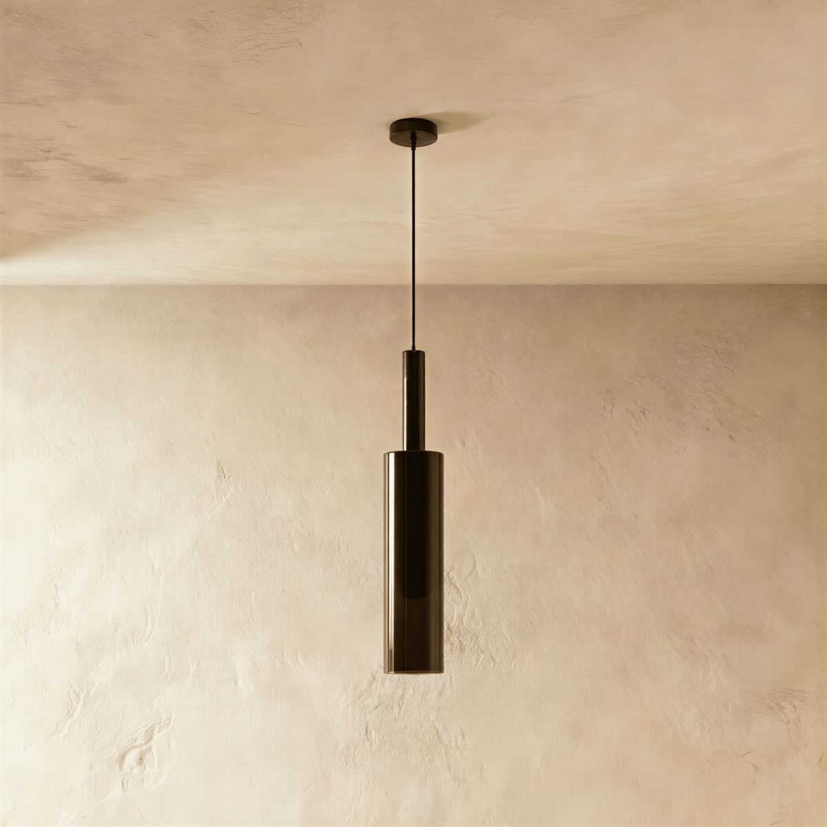 Unlit and straight-on, the black-tinted glass pendant's cylindrical shade hangs against a bare plaster wall, Clérachic hero shot.