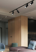 Clérachic black track with several spotlight heads on a ceiling above a timber-clad column and a mauve sofa.