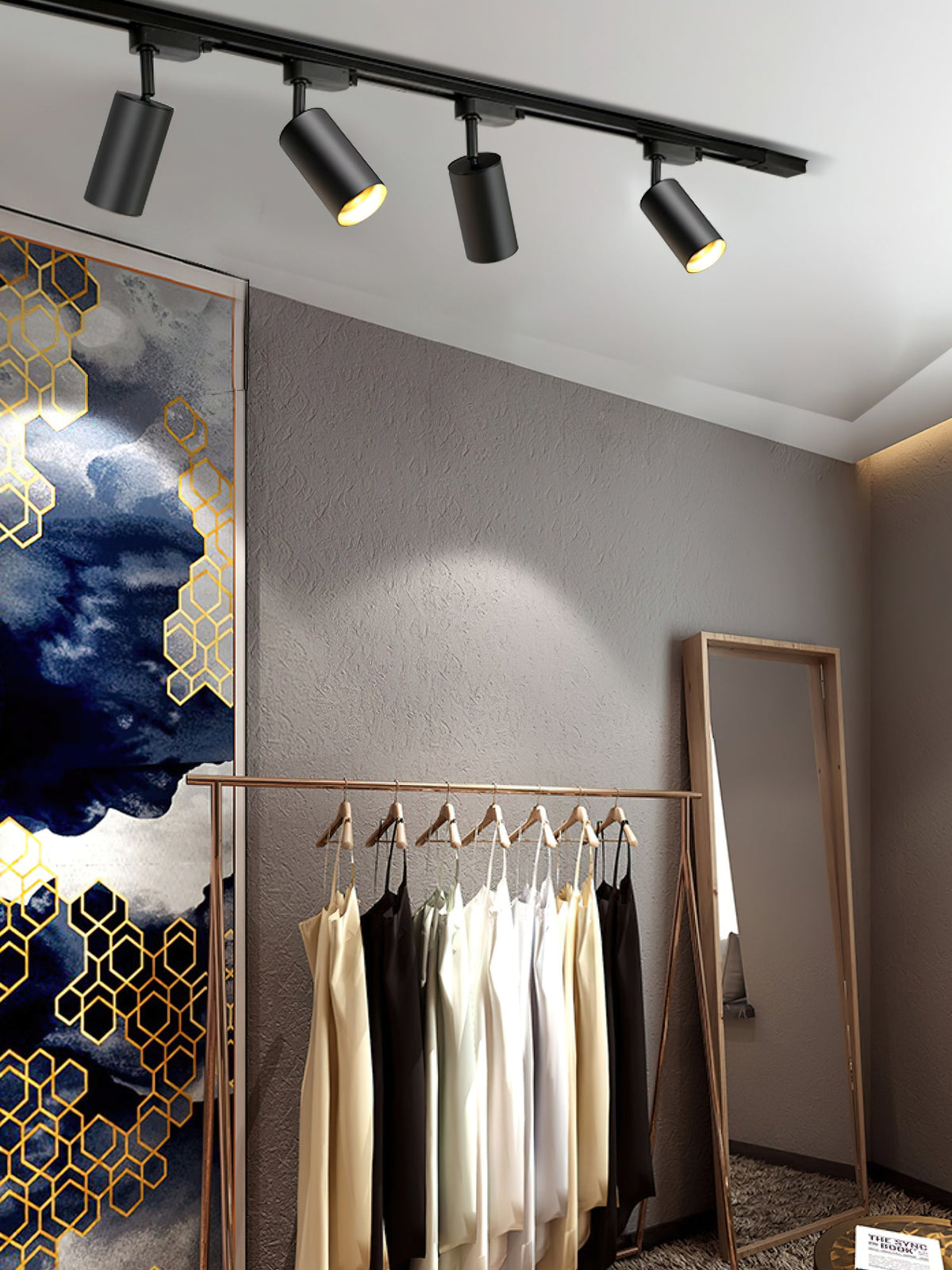 Four black Clérachic track spotlights above a clothing rail and a wooden mirror, with a patterned panel at the side.