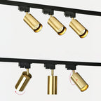 Close views of gold Clérachic spotlight heads on a black track, with red arrows showing how each one tilts and turns.