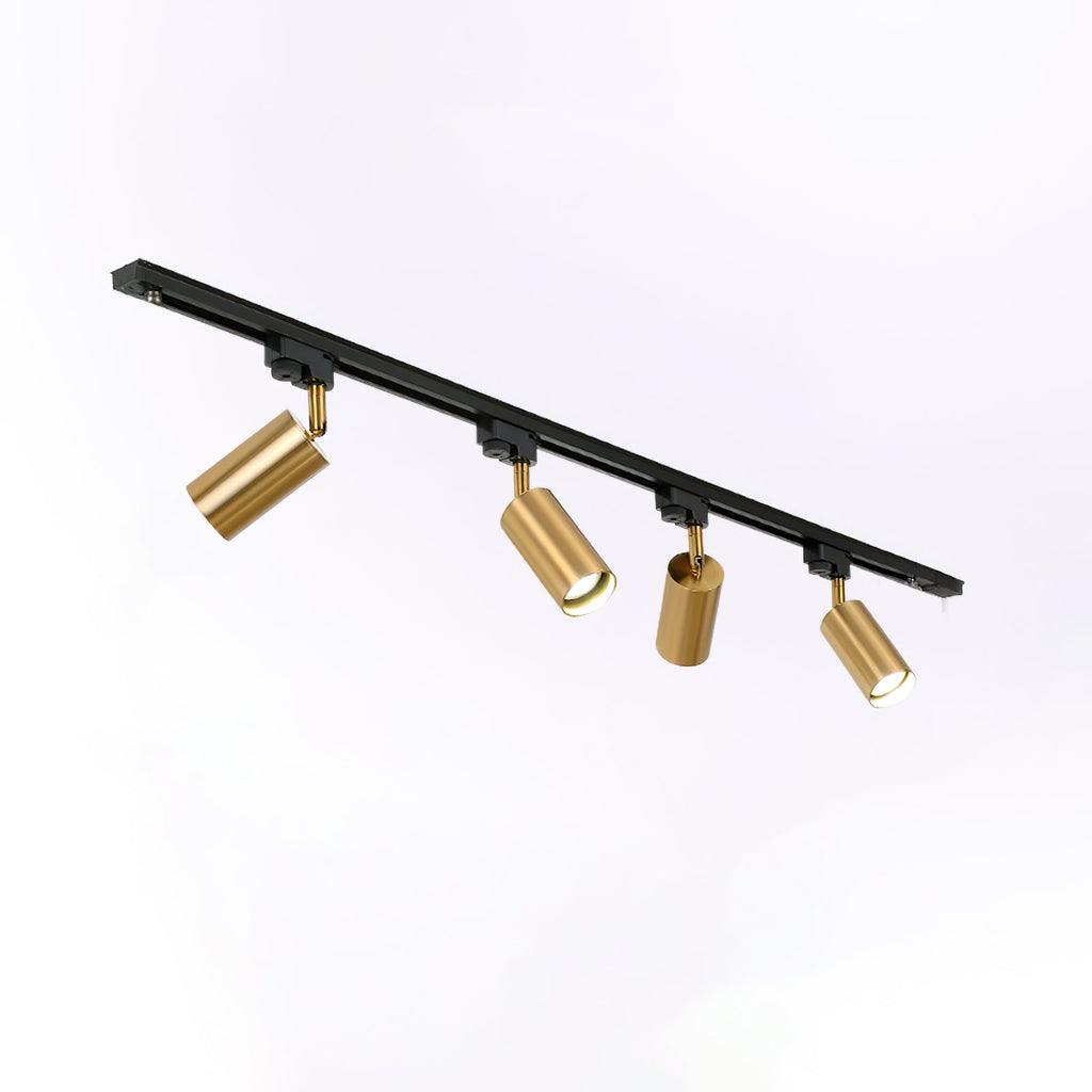 Four gold Clérachic spotlights on an angled black track, each head tilted differently, on a pale backdrop.
