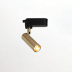 Single gold Clérachic spotlight on a slim stem with a black adaptor, lit and tilted on a plain background.