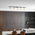 Five gold Clérachic spotlights on a black track, above a dark panelled wall with open shelves and a marble table.